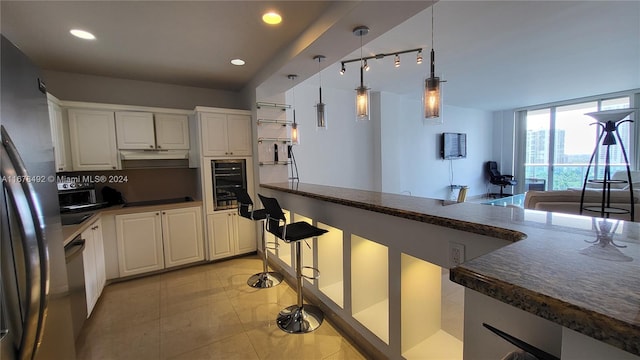 kitchen featuring backsplash, light tile patterned floors, white cabinetry, black appliances, and decorative light fixtures