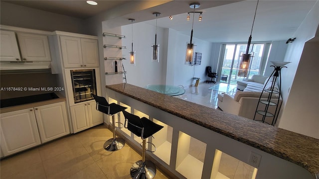 kitchen featuring white cabinets, hanging light fixtures, dark stone countertops, and light tile patterned floors