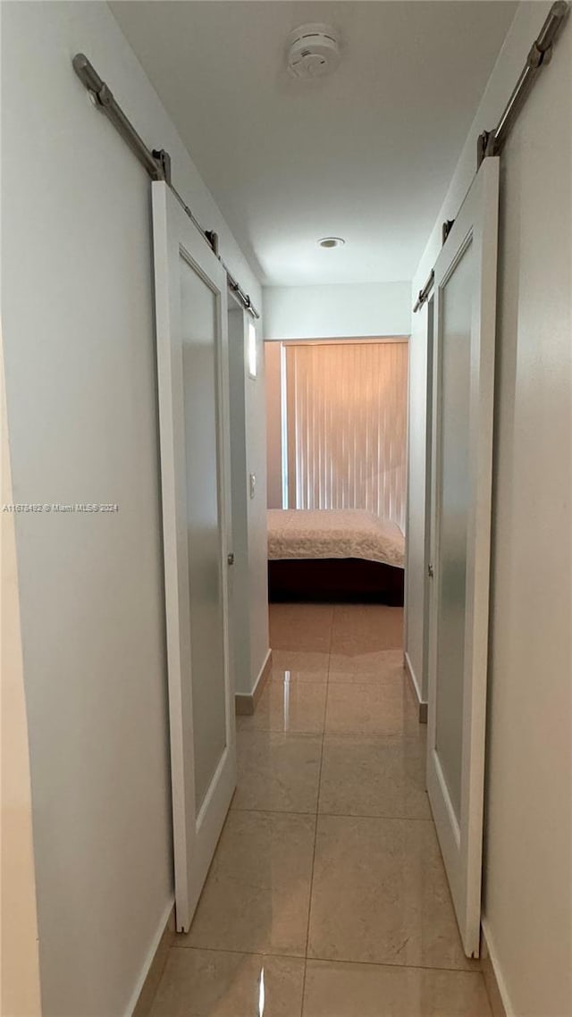 corridor featuring a barn door and light tile patterned floors