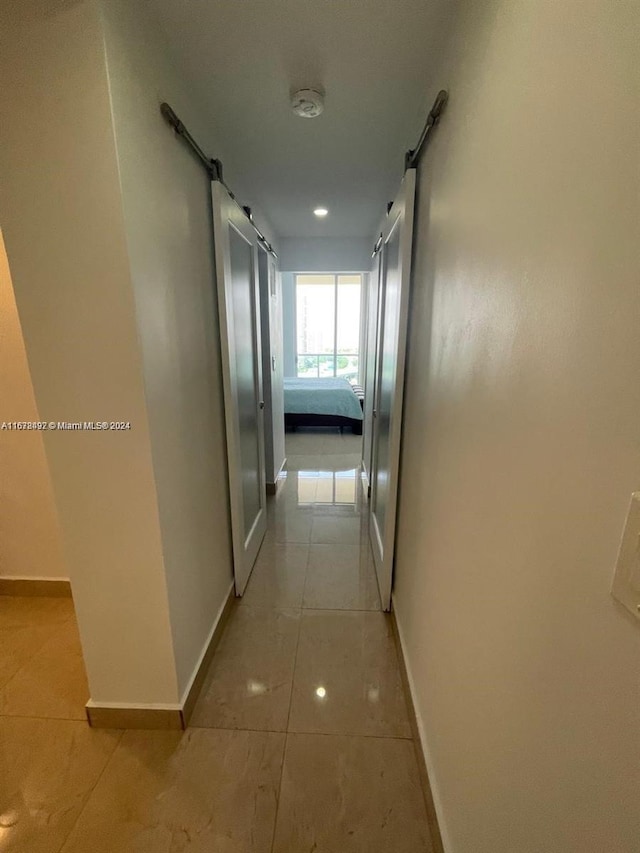 corridor featuring a barn door and light tile patterned floors