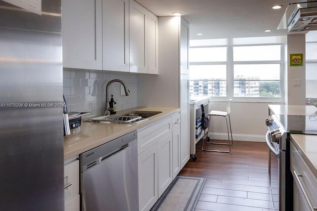 kitchen featuring white cabinetry, sink, dark hardwood / wood-style floors, backsplash, and appliances with stainless steel finishes