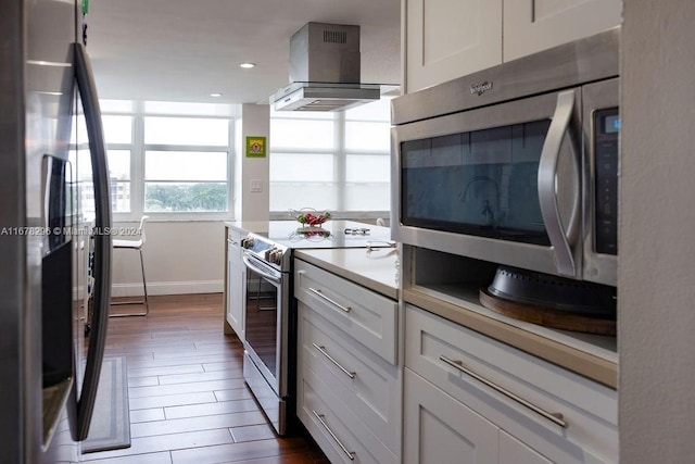 kitchen featuring white cabinetry, dark wood-type flooring, stainless steel appliances, and wall chimney range hood