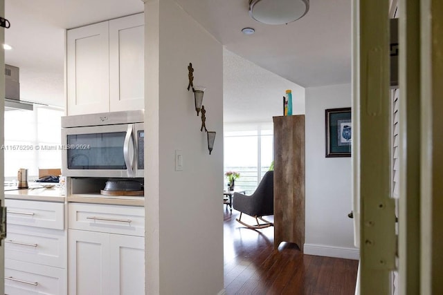 kitchen featuring appliances with stainless steel finishes, white cabinetry, dark wood-type flooring, and range hood