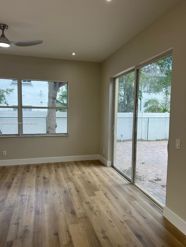 unfurnished room with a wealth of natural light, light wood-type flooring, and ceiling fan