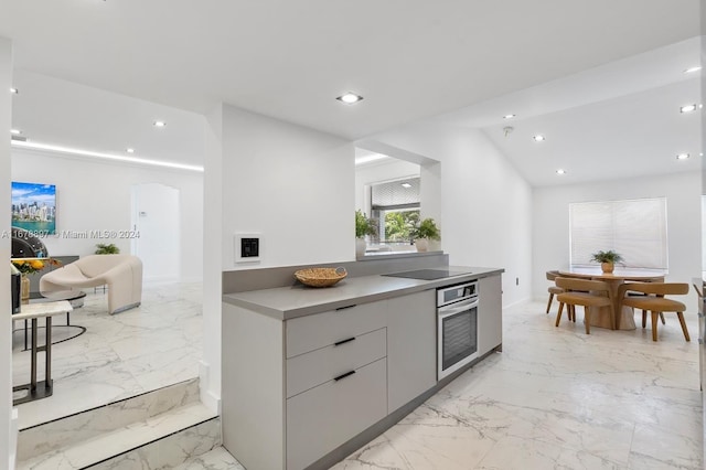 kitchen featuring lofted ceiling, gray cabinetry, and oven