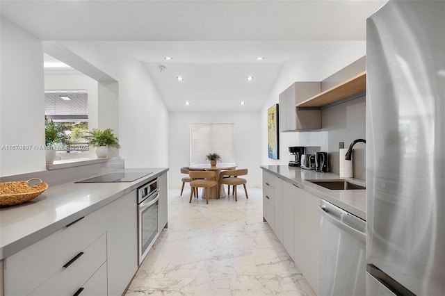 kitchen featuring sink, appliances with stainless steel finishes, white cabinetry, and vaulted ceiling