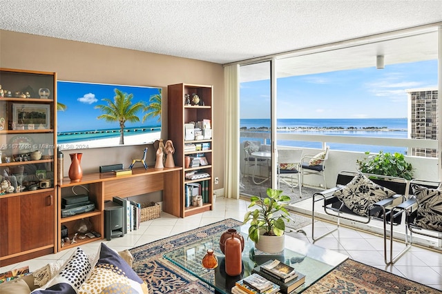 living room featuring a view of the beach, a water view, a healthy amount of sunlight, and light tile patterned floors