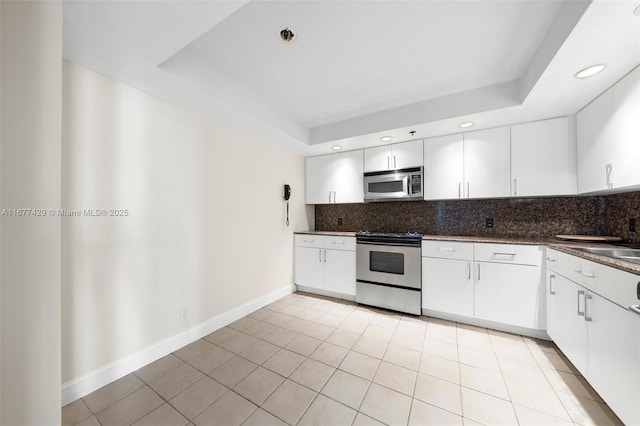 1627 Brickell Ave Unit 1906, Miami, FL 33129 - kitchen featuring appliances with stainless steel finishes, dark countertops, backsplash, a tray ceiling, and recessed lighting