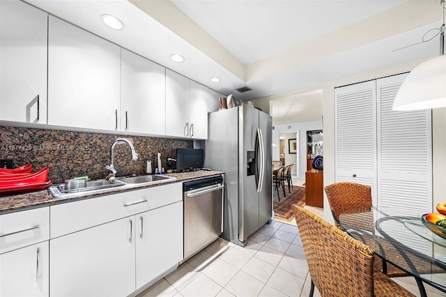 kitchen featuring tasteful backsplash, sink, light tile patterned flooring, white cabinetry, and stainless steel appliances