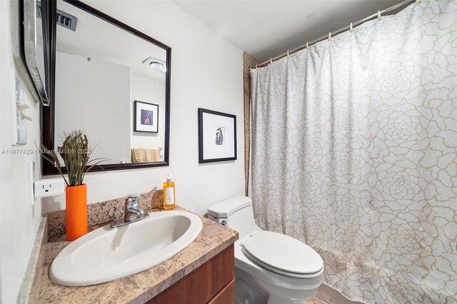 bathroom with toilet, vanity, and a shower with shower curtain