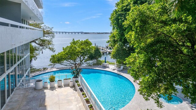 view of pool with a water view and a patio