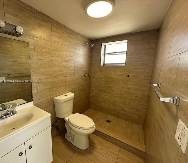 bathroom with toilet, tile walls, a tile shower, tile patterned floors, and vanity