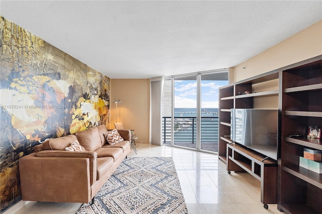 living room featuring a wall of windows, a textured ceiling, and light tile patterned floors