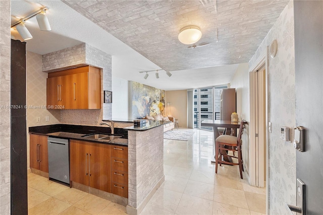 kitchen with dishwasher, track lighting, kitchen peninsula, sink, and light tile patterned floors