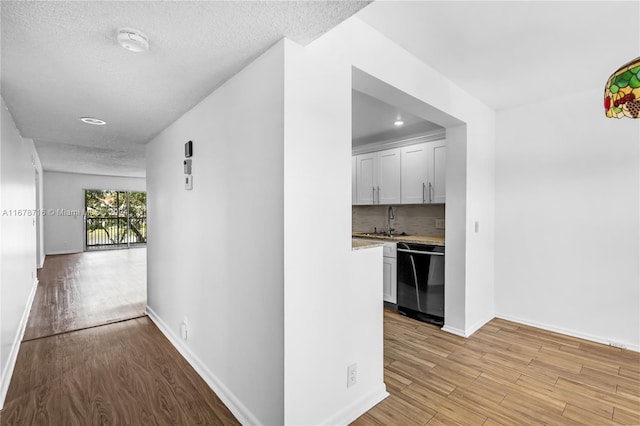 hall with sink, a textured ceiling, and light hardwood / wood-style floors