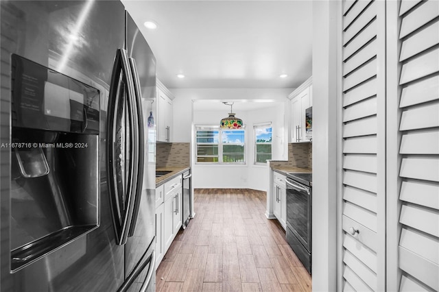 kitchen featuring appliances with stainless steel finishes, white cabinetry, decorative light fixtures, and backsplash