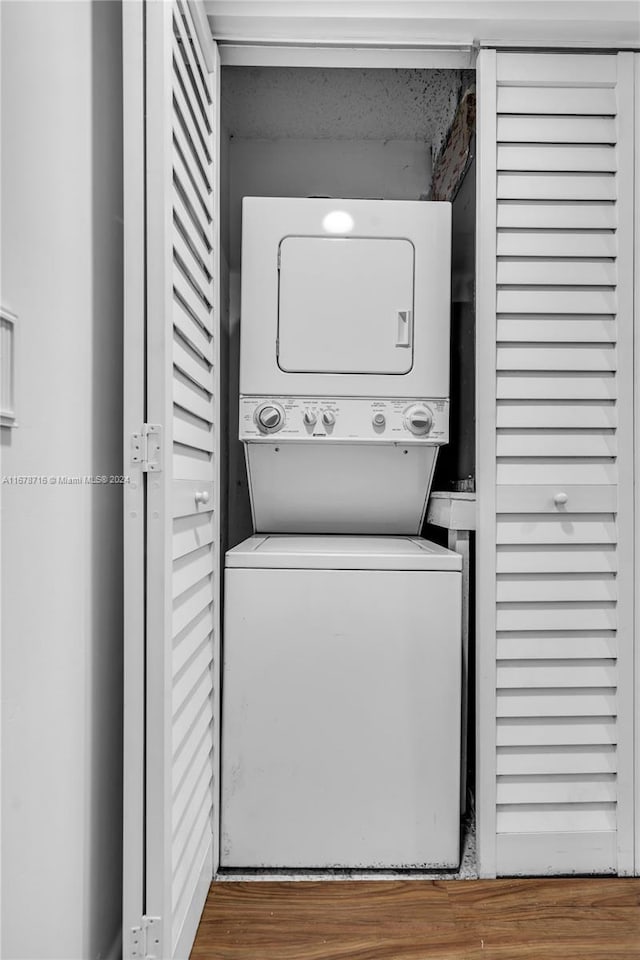 laundry area with hardwood / wood-style floors and stacked washer / drying machine