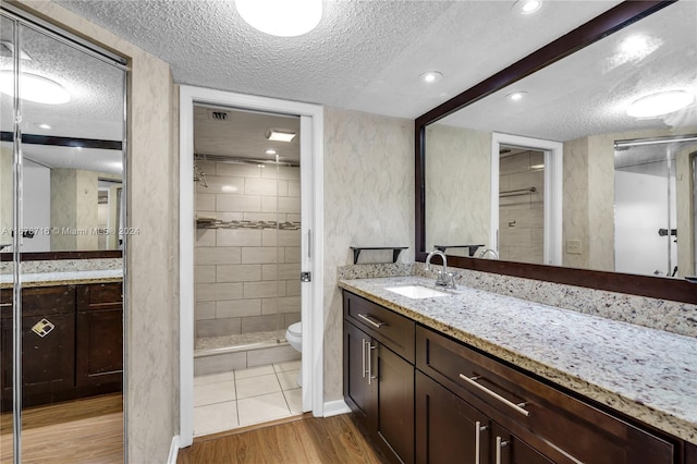 bathroom featuring vanity, hardwood / wood-style floors, a textured ceiling, and toilet