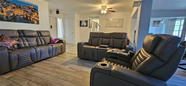 living room with ceiling fan, wood-type flooring, and a textured ceiling