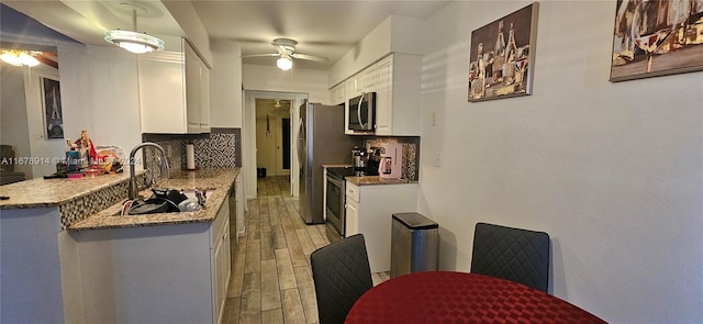 kitchen with sink, decorative backsplash, stainless steel appliances, and white cabinets