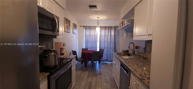 kitchen with dark wood-type flooring, stainless steel appliances, sink, and white cabinets