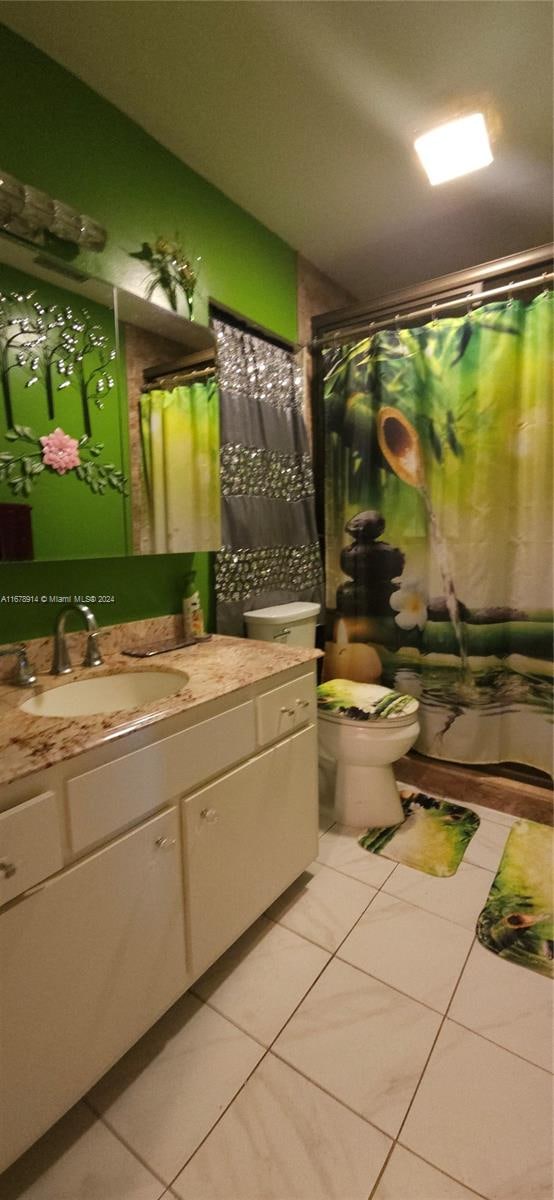 full bathroom featuring vanity, shower / bath combo with shower curtain, toilet, and tile patterned floors