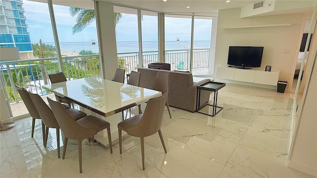 dining area with expansive windows and a beach view