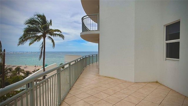 balcony with a water view and a view of the beach