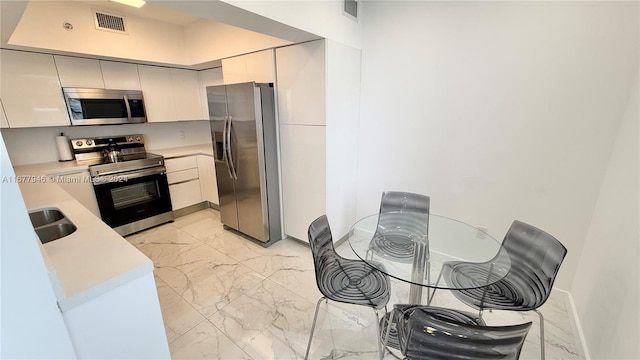 kitchen featuring sink, appliances with stainless steel finishes, and white cabinetry