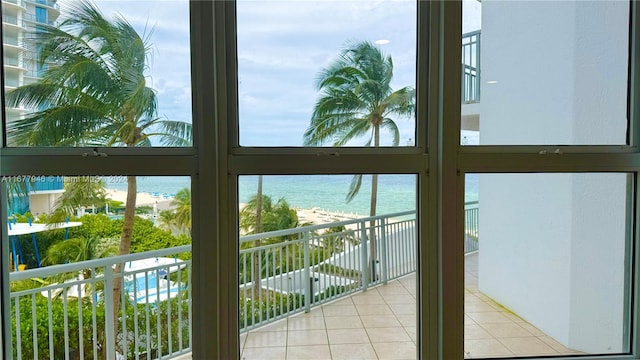 doorway to outside featuring a water view, a view of the beach, and light tile patterned floors