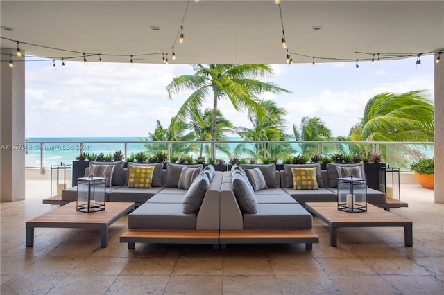 view of patio / terrace with a balcony, outdoor lounge area, a water view, and a view of the beach