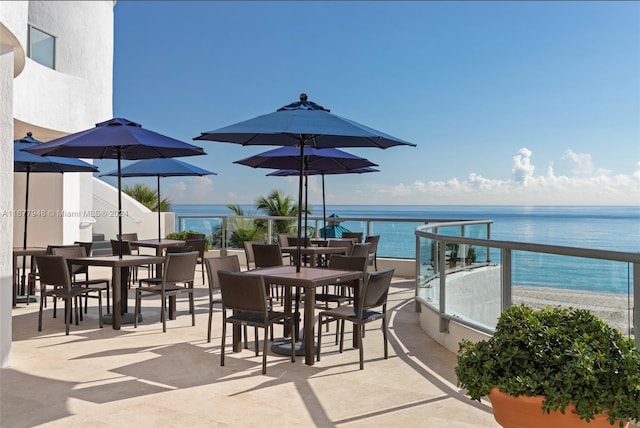 view of patio / terrace with a balcony, a water view, and a beach view