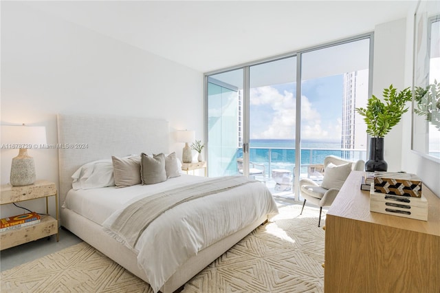 bedroom featuring access to exterior, floor to ceiling windows, a water view, and multiple windows