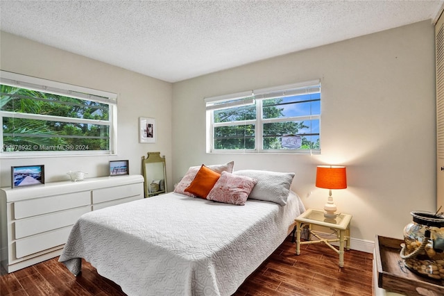 bedroom featuring dark wood-type flooring, multiple windows, and a textured ceiling