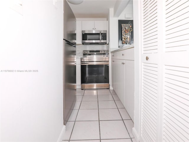 kitchen with light tile patterned floors, appliances with stainless steel finishes, and white cabinetry