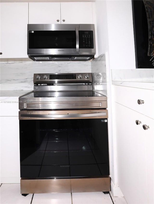 kitchen with light tile patterned floors, stainless steel appliances, and white cabinetry