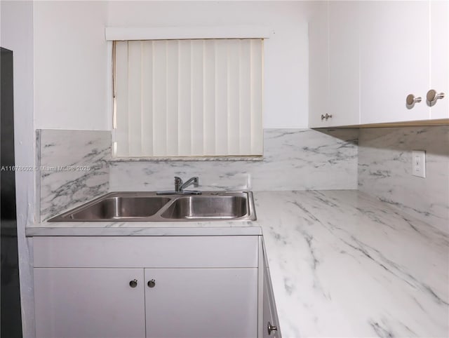 kitchen featuring white cabinets, backsplash, and sink