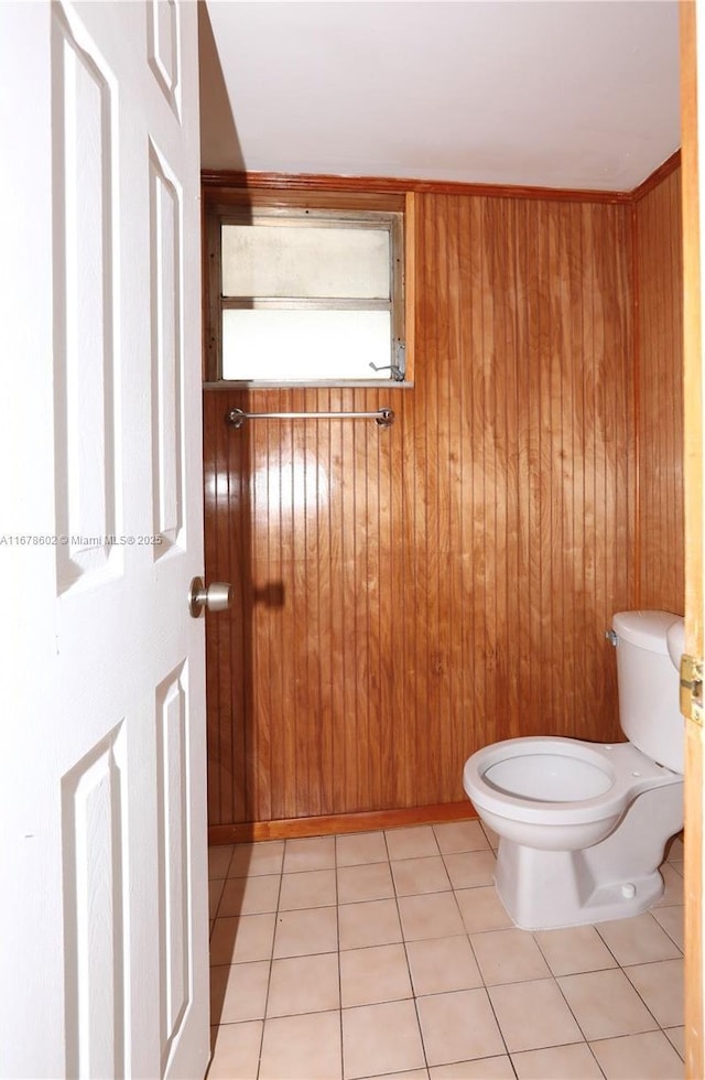 bathroom with tile patterned floors, wood walls, and toilet