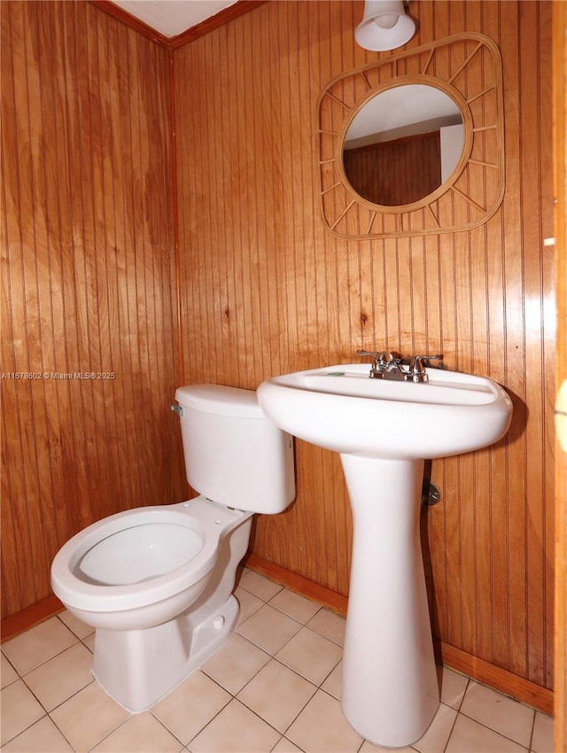 bathroom with toilet, tile patterned floors, and wood walls