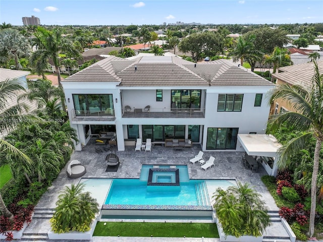 rear view of property featuring a patio, a pool with hot tub, and a balcony