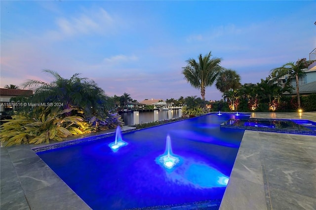 pool at dusk featuring a patio area and a water view