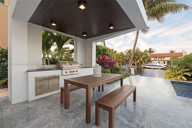 view of patio with a water view, sink, an outdoor kitchen, and grilling area