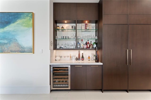 bar featuring dark brown cabinetry, light tile patterned floors, and beverage cooler