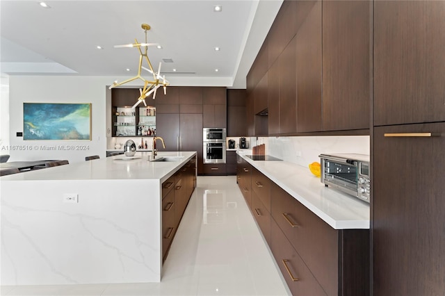 kitchen featuring tasteful backsplash, light tile patterned floors, pendant lighting, sink, and stainless steel double oven