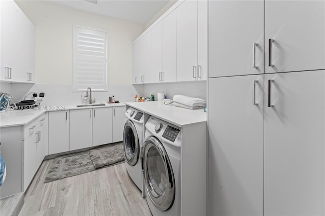 clothes washing area featuring cabinets, light hardwood / wood-style flooring, sink, and washer and clothes dryer