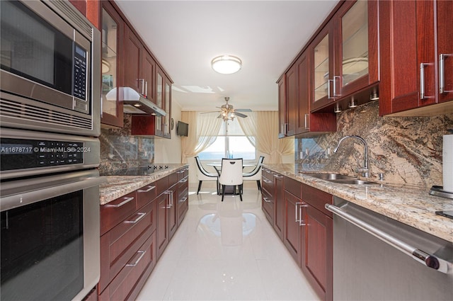 kitchen with light stone countertops, appliances with stainless steel finishes, ceiling fan, and sink