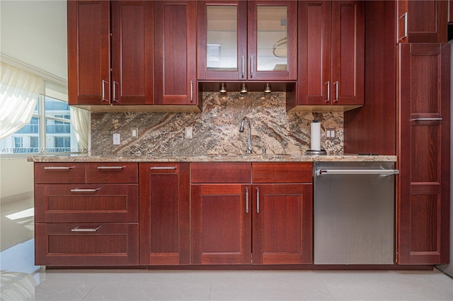 bar featuring backsplash, sink, stainless steel dishwasher, light stone countertops, and light tile patterned floors