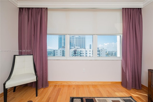 living area featuring hardwood / wood-style flooring, crown molding, and a healthy amount of sunlight