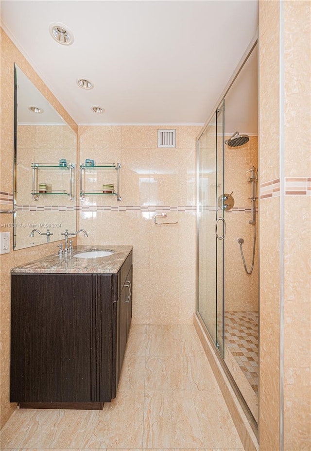 bathroom featuring vanity, walk in shower, and tile walls