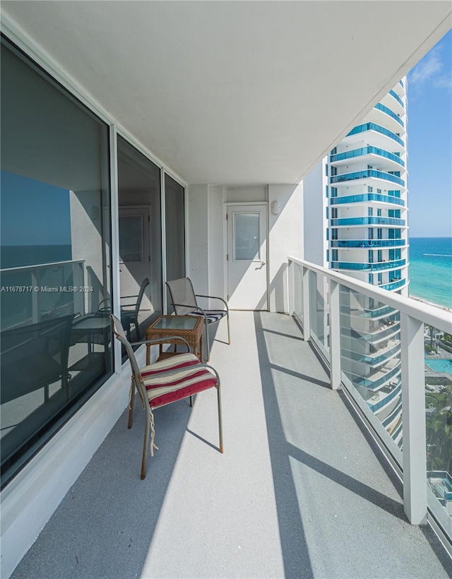 balcony featuring a water view and a beach view